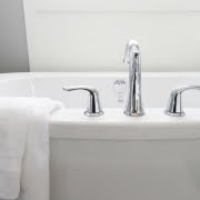 A picture of a bath tub with silver taps and a towel draped over the edge