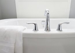 A picture of a bath tub with silver taps and a towel draped over the edge