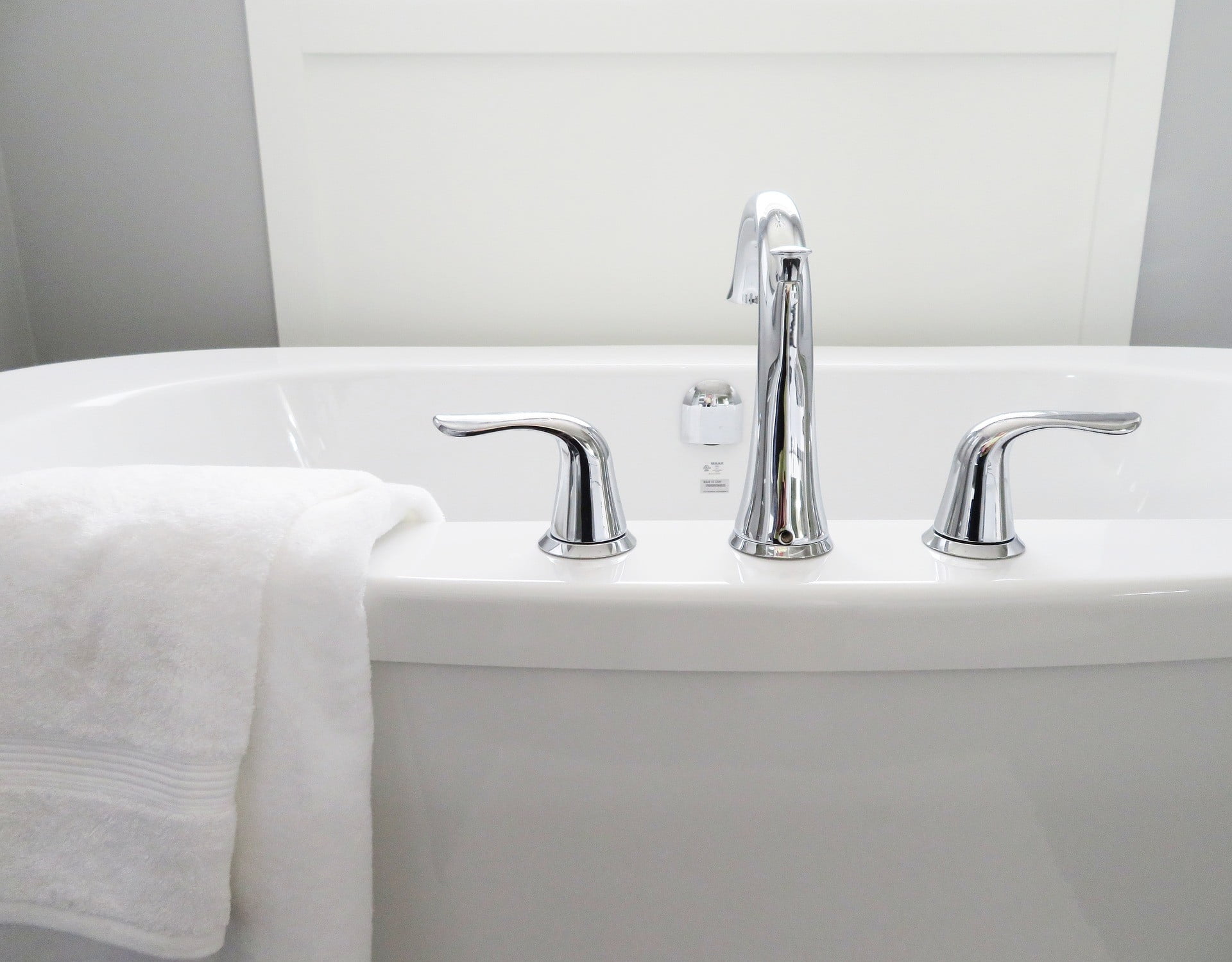 A picture of a bath tub with silver taps and a towel draped over the edge