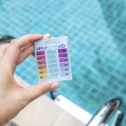 mini water testing kit over blurred swimming pool background Woman's hand holding a mini water testing kit over blurred swimming pool background